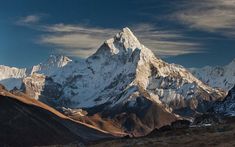 the mountains are covered in snow and brown grass