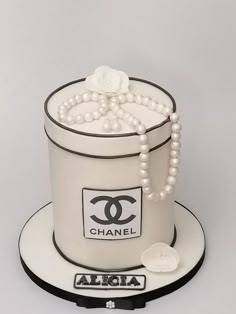 a chanel hat cake with pearls and beads on the top is shown in white