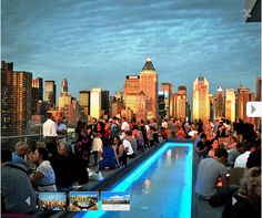 a group of people standing on top of a roof next to a pool in front of tall buildings