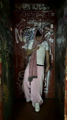 a man in pink pants and a white t - shirt is looking at his cell phone