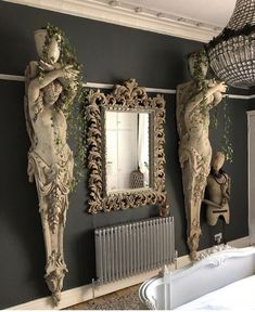 two statues are on the wall next to a mirror and radiator in a room