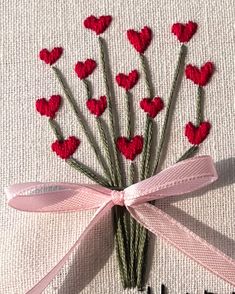 a bunch of small red hearts on top of a pink ribbon