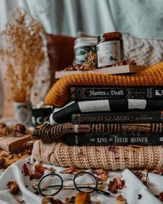 a stack of books sitting on top of a table next to glasses and other items