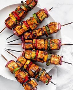 several skewers of food on a white plate