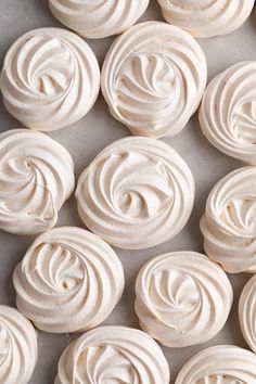 white frosted cupcakes with swirl designs on top are shown in close up
