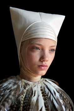 a woman wearing a white headdress with feathers on it