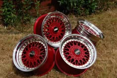 four red wheels are stacked on top of each other in front of some grass and bushes