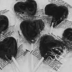 six black heart shaped lollipops wrapped in cellophane and sitting on top of each other