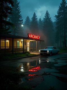 a car is parked in front of a motel at night with the lights on and it's red
