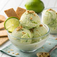 two bowls filled with ice cream next to crackers and limes on the table