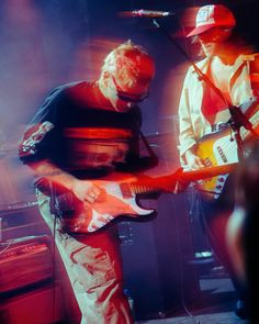 two men are playing guitars on stage