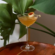 a drink sitting on top of a wooden table next to a green leafy plant