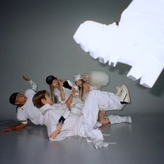 a group of people laying on top of each other in front of a white object