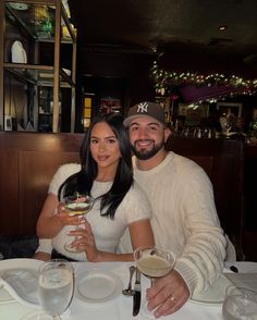 a man and woman sitting at a table with wine glasses