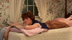 a woman laying on top of a bed next to a window