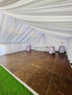 an empty dance floor with white drapes and chandeliers on the ceiling is set up for a wedding reception