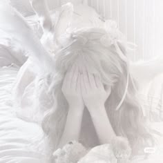 a woman laying in bed with her head on her hands and covering her face from the wind