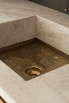a sink in a bathroom with marble counter top and gold faucet on the side