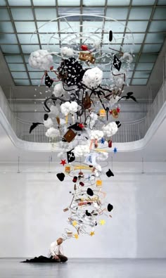 a man sitting on the ground under a chandelier with balloons hanging from it