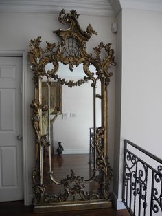 an ornate gold framed mirror sitting on top of a wooden floor next to a doorway