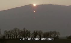 the sun is setting over a mountain with trees and hills in the background that reads, a life of peace and quiet