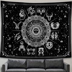a black and white tapestry with zodiac signs on it's wall hanging above a couch