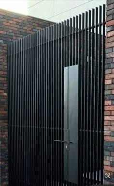 a black door is in between two brick walls with bars on the top and bottom