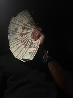 a person holding money in their hand with the light shining down on them and dark background