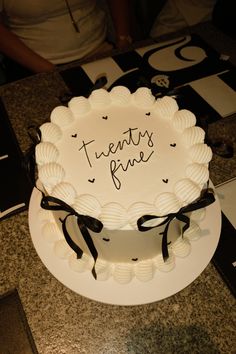 there is a white cake with black ribbon around it that says twenty nines prime