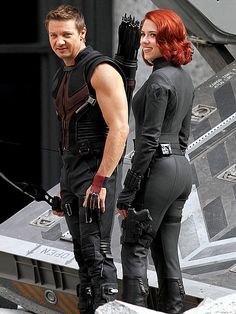 a man and woman dressed in black standing next to each other on top of a plane