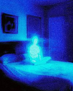 a blurry image of a person sitting on a bed in a room with blue lighting