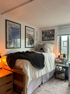 a bed sitting in a bedroom next to a window with pictures on the wall above it