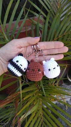 three crocheted keychains are hanging from a palm tree