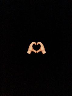 two hands making a heart shape in the dark