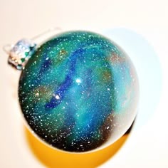 a glass ornament sitting on top of a white table next to a yellow plate