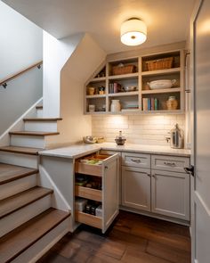 an open cabinet under the stairs in a kitchen
