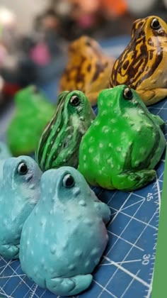 five different colored frogs sitting on top of a cutting board