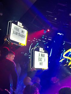 people at a club with neon signs above their heads and lights on the ceiling behind them