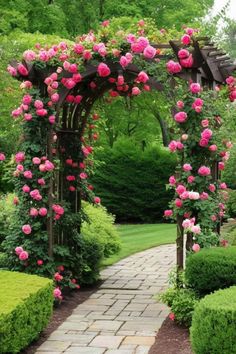 a garden with pink roses on the arbor and stone walkway leading to an open area