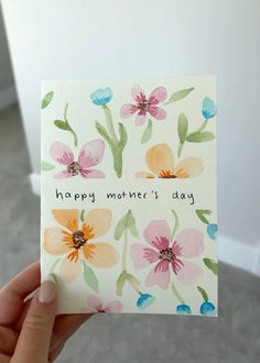 a hand holding up a card with flowers on it that says happy mother's day