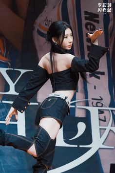 a woman in black top and shorts on stage with her legs spread out to the side