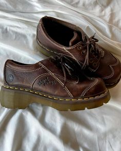 a pair of brown shoes sitting on top of a bed