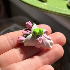 a person is holding a tiny flower in their left hand, with other items on the table behind them