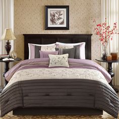 a bed with purple and white comforters in a bedroom