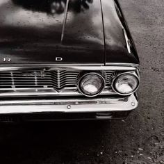 an old black and white photo of the front end of a car with its lights on