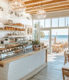 the inside of a restaurant with tables, chairs and an ocean view in the background