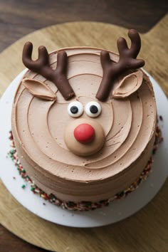 a chocolate cake with frosting and reindeer's head on top, sitting on a wooden table