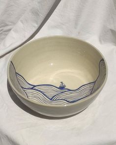 a bowl with a boat on it sitting on a white tablecloth covered table cloth