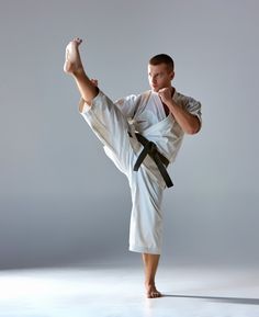 a man is doing karate on a white background with his leg up in the air