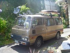 an old van with a surfboard on the roof parked in front of a house